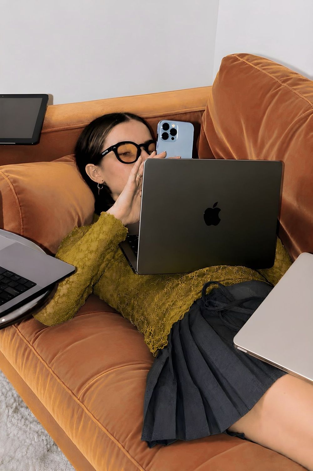 A founder working from the sofa, laptop and phone in hand