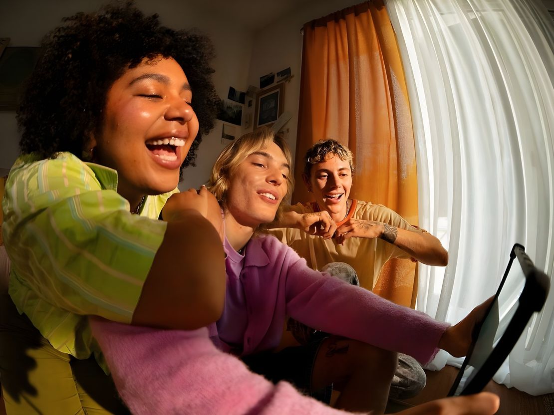 Three colleagues laughing together over a tablet